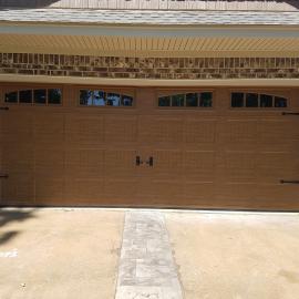 Residential garage door with ornamental hardware and windows